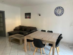 a living room with a table and a clock on the wall at A deux pas du Rhone in Sault-Brénaz