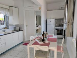 a kitchen with white cabinets and a table and chairs at Katerina's Countryside and Sea House in Nea Iraklia
