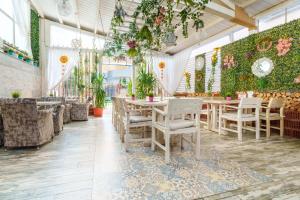 a restaurant with tables and chairs and plants at Camere de inchiriat KATALEYA in Mamaia Nord