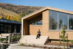 a woman sitting on the steps of a house at Abodo Alpine Eco Villa in Cardrona