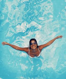 a woman is swimming in a swimming pool at Endless Memories for Large Groups in Private Jungle Retreat in Tanah Lot