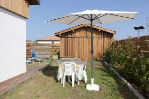 una mesa y sillas bajo una sombrilla en un patio en Dependance dans les Landes, en Escource