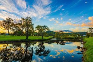 a body of water with trees and a cloudy sky at Willows Cottage on Anzac in Stanthorpe