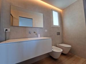 a bathroom with a tub and a toilet and a mirror at "Le chic" sulla duna fronte mare in Follonica