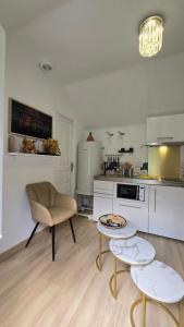a white kitchen with two tables and a chair at La Perle Rare in Massy