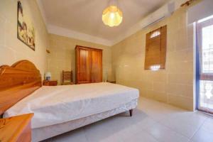 Un dormitorio con una gran cama blanca y una ventana. en An excellent getaway choice, in the midst of Qbajjar and Marsalforn Bay!, en Żebbuġ