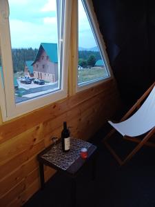 a bottle of wine sitting on a table next to two windows at Apartments Igor in Žabljak