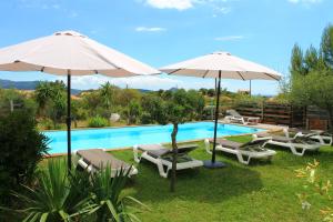 a swimming pool with umbrellas and chairs and a swimming pool at Caseddu Di Poggiale in Figari