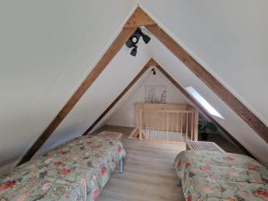 a attic room with two beds and a crib at Huisje in Pieterburen in Pieterburen