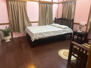 a bedroom with a bed and a table and curtains at Heritage House Shillong in Shillong