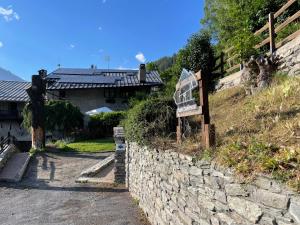 a stone wall next to a house with a sign at Chalet Bellevue in Bardonecchia