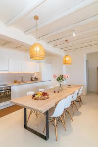 a kitchen and dining room with a wooden table and chairs at Dolce Villa Tinos - Kardiani - Stone & Sunset Views in Kardiani +13 photos