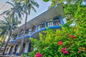 a building with blue balconies and palm trees at Baga Beach Palms in Baga