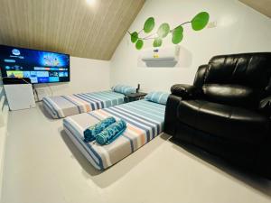 a living room with two beds and a couch and a tv at Tierra Bukid en Amadeo in Cavite