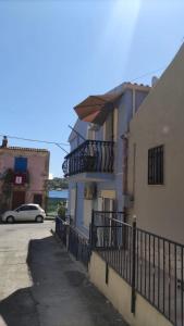 a building with a balcony and a car parked next to it at Trinacrie Home's in Brucoli