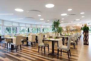 a dining room with tables and white chairs at Laguna Park Hotel 4Superior in Bibione