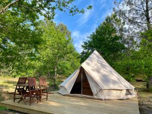 卡尔康Camping la Kahute - Tente tipi au coeur de la fôret的帐篷配有椅子和一张桌子,位于甲板上