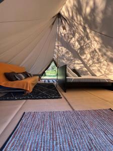 卡尔康Camping la Kahute - Tente tipi au coeur de la fôret的一个带床和地毯的帐篷