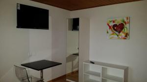 Zimmer mit einem Tisch und einem TV an der Wand in der Unterkunft good bed biberist in Biberist