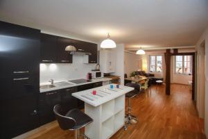 una cucina con armadi neri e piano di lavoro bianco di Appartements des 2 Têtes a Colmar
