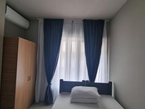 a bedroom with a bed with blue curtains and a window at Marald Eforie Nord in Eforie Nord