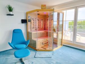 a room with a glass cabinet and a blue chair at Seeblickapartment für bis zu 12, Nürnberg & Schwabach in 30-35 Minuten zu erreichen, Sauna, Arbeitsplatz, Dachterrasse & Grill in Spalt