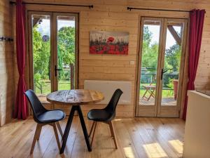 a room with a table and chairs in a cabin at Le Coquelicot - Châlet avec SPA in Trainel