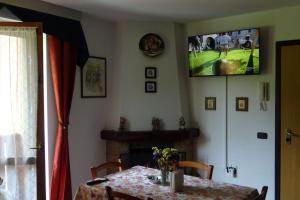 a dining room with a table and a television on the wall at Chalet Belvedere in Costa di Serina