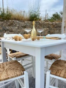 a white table with wine glasses and a bottle on it at Brizo - TCupStudios in Kythira