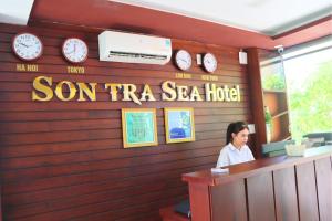 a woman standing at a counter in a restaurant with clocks at Sontra Sea Hotel in Danang
