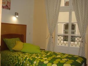 a bedroom with a bed with a green comforter and a window at DownTown Guest House in Lisbon