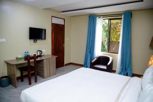 ein Hotelzimmer mit Bett, Schreibtisch und Fenster in der Unterkunft Greenside Hotel in Arusha