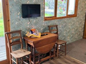 a wooden table with two chairs and a television on a wall at Country garden lodge on Devon Cornwall border in Lifton