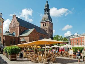 a group of tables and chairs and a building with a clock tower at Cheap And Chic in Rīga