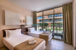 ein Hotelzimmer mit zwei Betten und einem großen Fenster in der Unterkunft Apartments Herdade dos Salgados by PCFerias in Albufeira + 144 Fotos