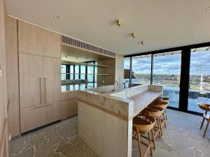 a kitchen with a large counter with chairs and windows at Horizon Bliss Apartment in Frankston