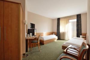 a hotel room with two beds and a desk at Semiramis Business Hotel in Szolnok