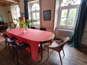 a red table and chairs in a room with windows at La Tocade Del Arte - Dinan in Lanvallay