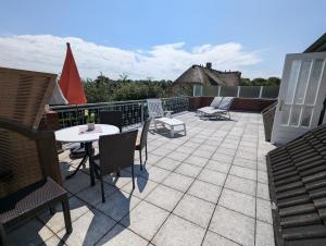 a patio with a table and chairs on a roof at Haus Dorfschmiede, Wohnung Anker in Alkersum