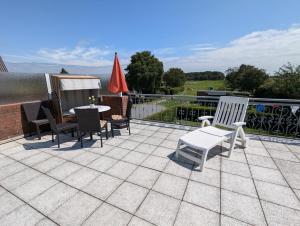 a patio with chairs and tables on a roof at Haus Dorfschmiede, Wohnung Anker in Alkersum +13 photos