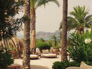 a patio with palm trees and chairs and the ocean at UNIO Ibiza - Adults Only in Cala Vadella