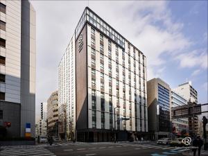 a tall building with many windows in a city at Daiwa Roynet Hotel Osaka Sakaisuji Honmachi PREMIER in Osaka