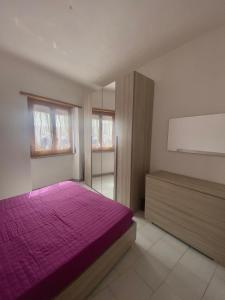 a bedroom with a purple bed and a window at La casa di DELFA in piazzetta in Aggius