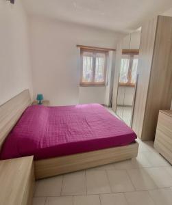 a bedroom with a bed with a purple comforter at La casa di DELFA in piazzetta in Aggius