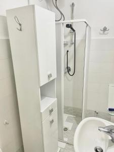 a white bathroom with a shower and a sink at La casa di DELFA in piazzetta in Aggius +9 photos