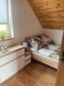 a bed in a small room with a wooden ceiling at Perły Roztocza - Domek całoroczny in Krasnobród