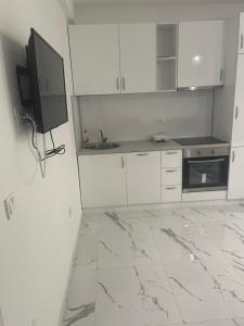 a kitchen with white cabinets and a tv on the wall at Morski plamen in Kruče