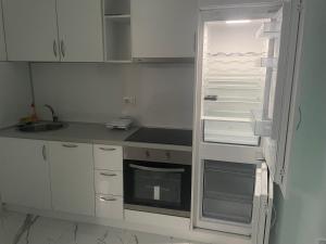 a kitchen with white cabinets and an empty refrigerator at Morski plamen in Kruče