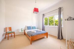 une chambre avec un lit, une fenêtre et une chaise dans l'établissement Casa Férias Charneca da Caparica, à Charneca