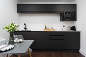 a kitchen with black cabinets and a table at Room 2 Hotel style Double bedroom in Marazion in Marazion